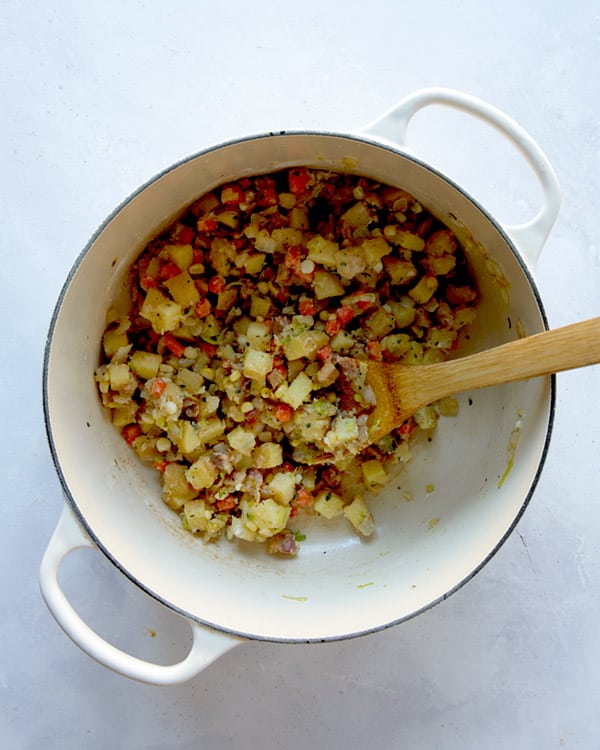 Cooking down the ingredients to make clam chowder in a pot.