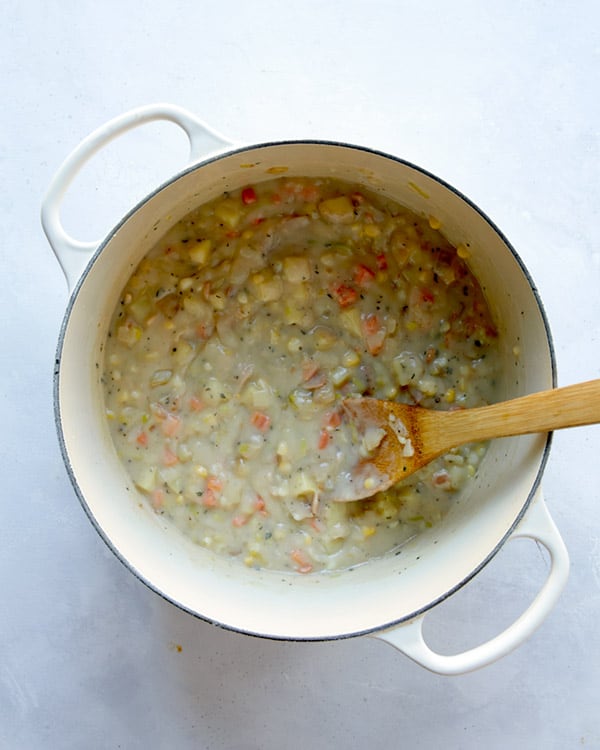 Clam chowder in a pot cooking down with stock.