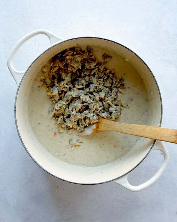 Clams being added to a pot to make clam chowder recipe.