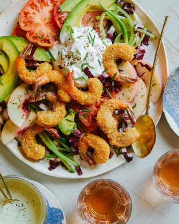 Fried coconut shrimp on top of a bed of lettuce and seasonal summer ingredients.