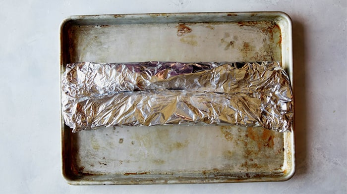 Ribs wrapped in tin foil on a baking sheet to make oven baked ribs.