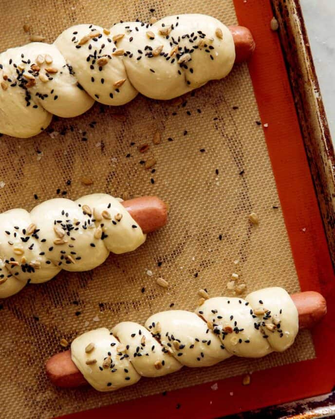 A close up of pretzel dogs on a baking sheet ready to go in the oven.