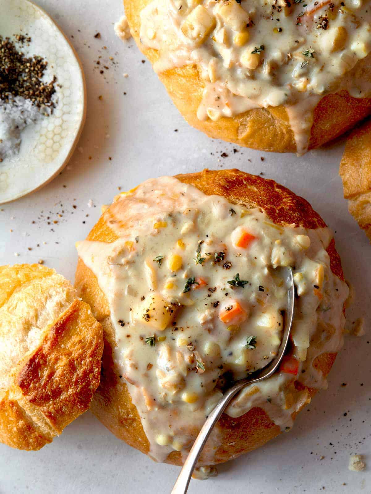 Clam chowder recipe in two bread bowls with a spoon in one.