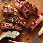 A close up on sticky oven baked ribs on a cutting board.