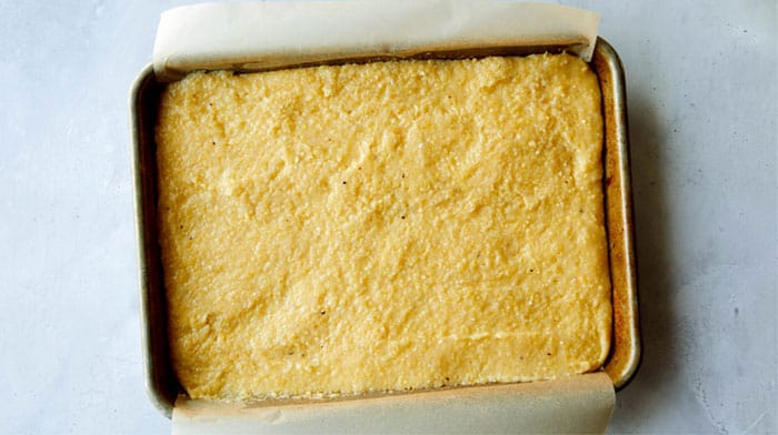 Cooked polenta spread evenly onto a baking sheet.