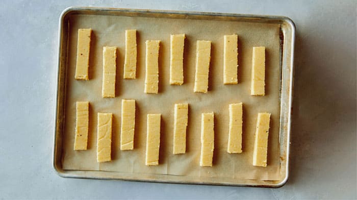 Polenta fries on a baking sheet ready to be baked.