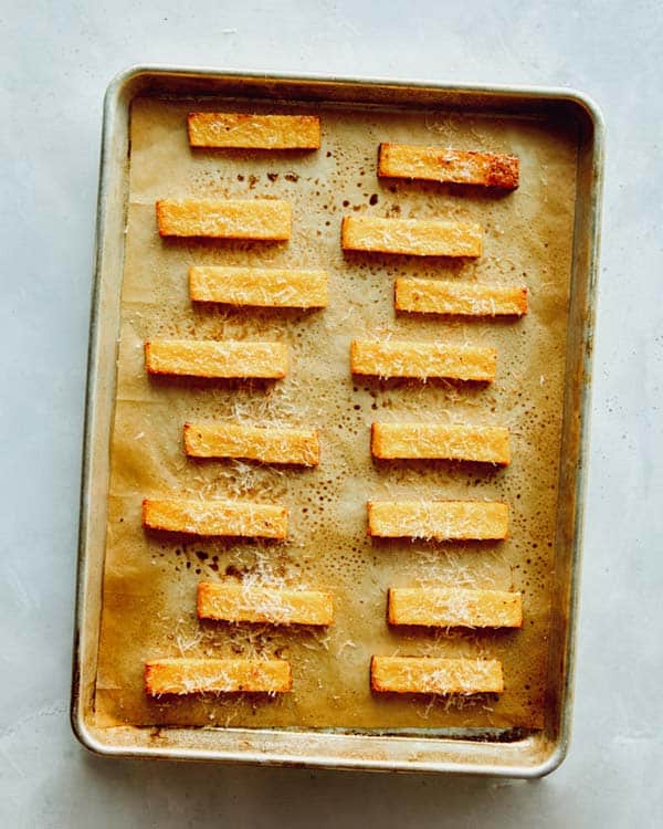 Baked polenta fries on a baking sheet.