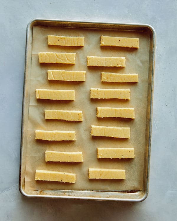 Polenta fries on a baking sheet waiting to be baked.