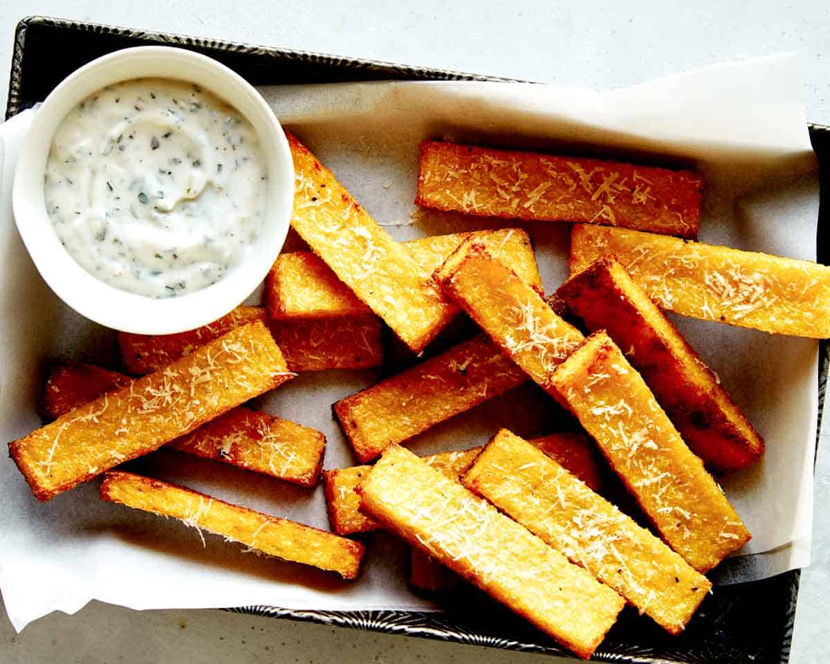 Polenta fries with parmesan in a basket with aioli.
