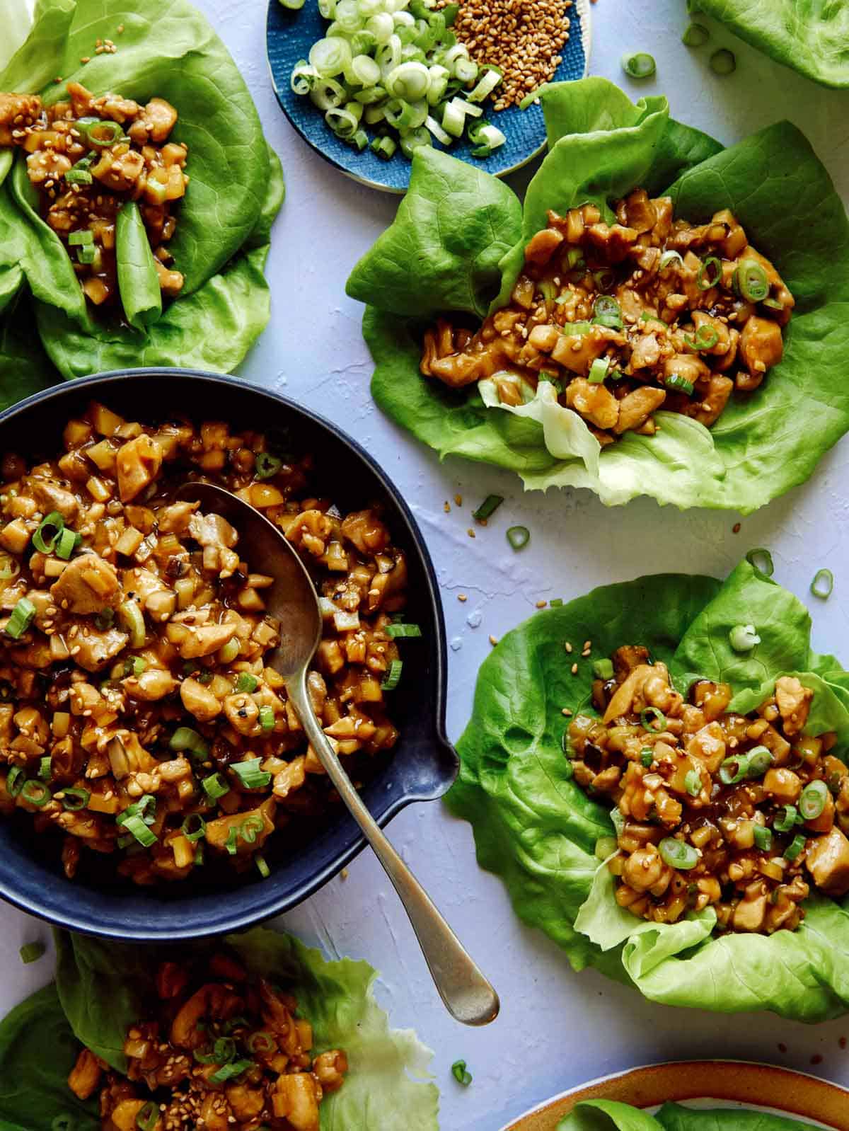 Chicken lettuce wraps with lettuce and chicken in them on the side. 