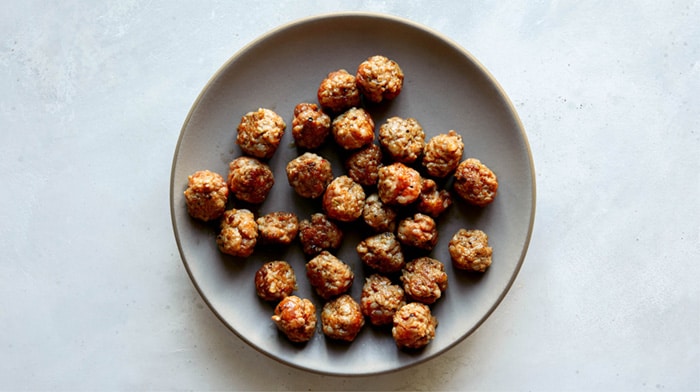 A plate of sausage meatballs on a kitchen counter.