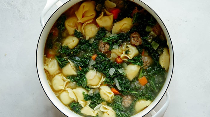 Tortellini soup ready to serve in a stock pot.