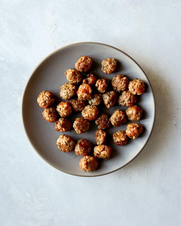 A plate of sausage meatballs on a kitchen counter.