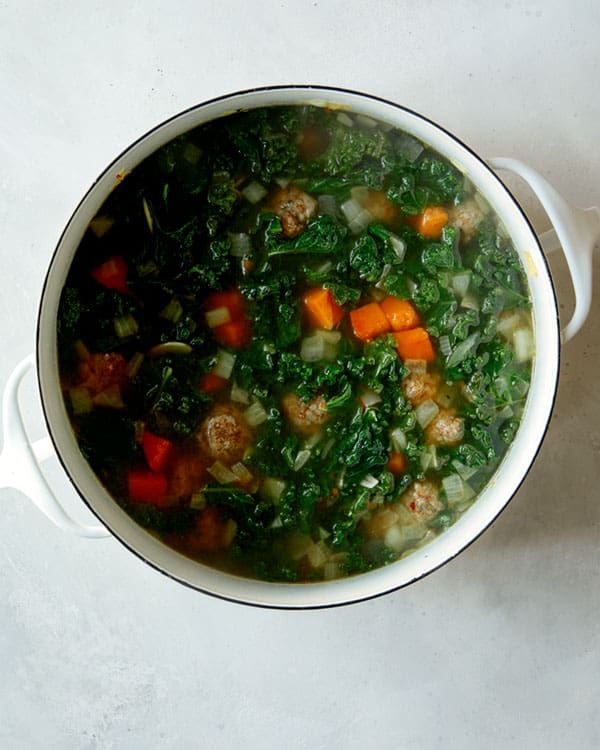 Tortelli soup in a stock pot on a kitchen counter.