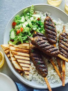 Lamb kofta on rice with pita triangles and salad.