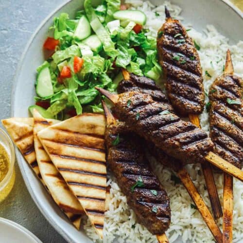 Lamb kofta on rice with pita triangles and salad.