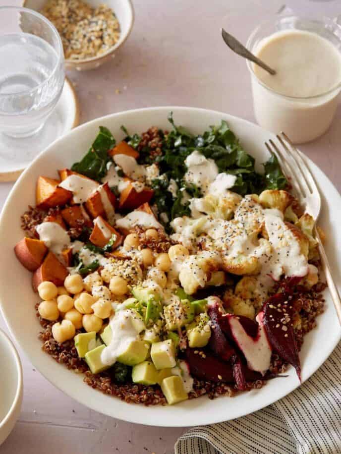 A light and fresh Buddha bowl topped with creamy garlic cashew sauce and a fork.