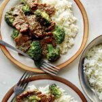 Beef and broccoli on plates with rice.