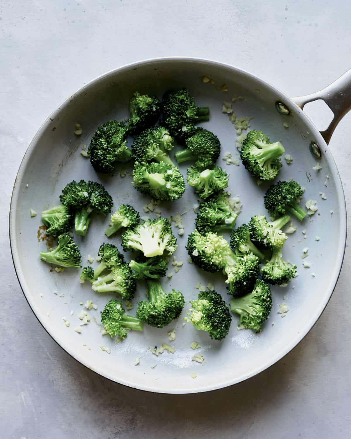 Broccoli and garlic cooking in a skillet.