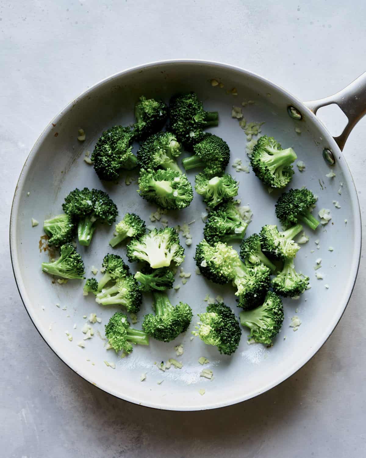 Broccoli and garlic cooking in a skillet. 