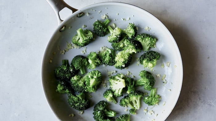 Broccoli and garlic cooking in a skillet.