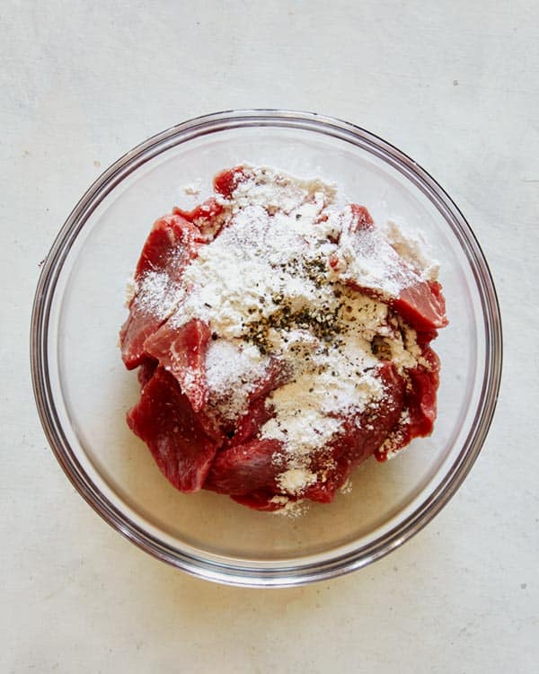 Beef slices in a glass bowl with cornstarch to make beef stroganoff.