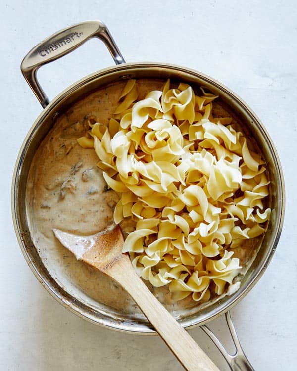 Beef stroganoff being mixed with egg noodles for the recipe.