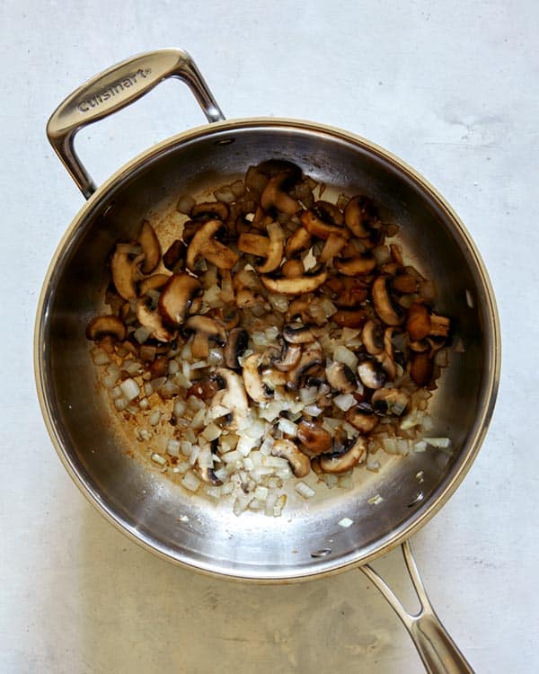 Onions and mushrooms in skillet cooking for beef stroganoff recipe.