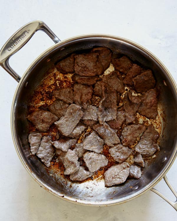 Beef cooking in a skillet for beef stroganoff.