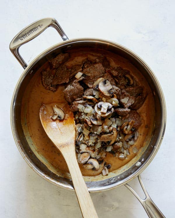 Beef stroganoff being mixed in a skillet.
