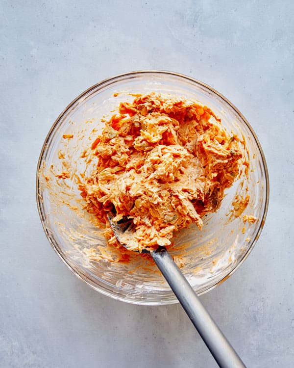 Ingredients for Buffalo Chicken Dip in a glass bowl combined.