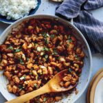 Cashew chicken recipe in a skillet with rice on the side.