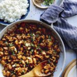 Cashew chicken recipe in a skillet with rice on the side.