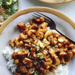 Cashew chicken with on two plates with forks and rice.