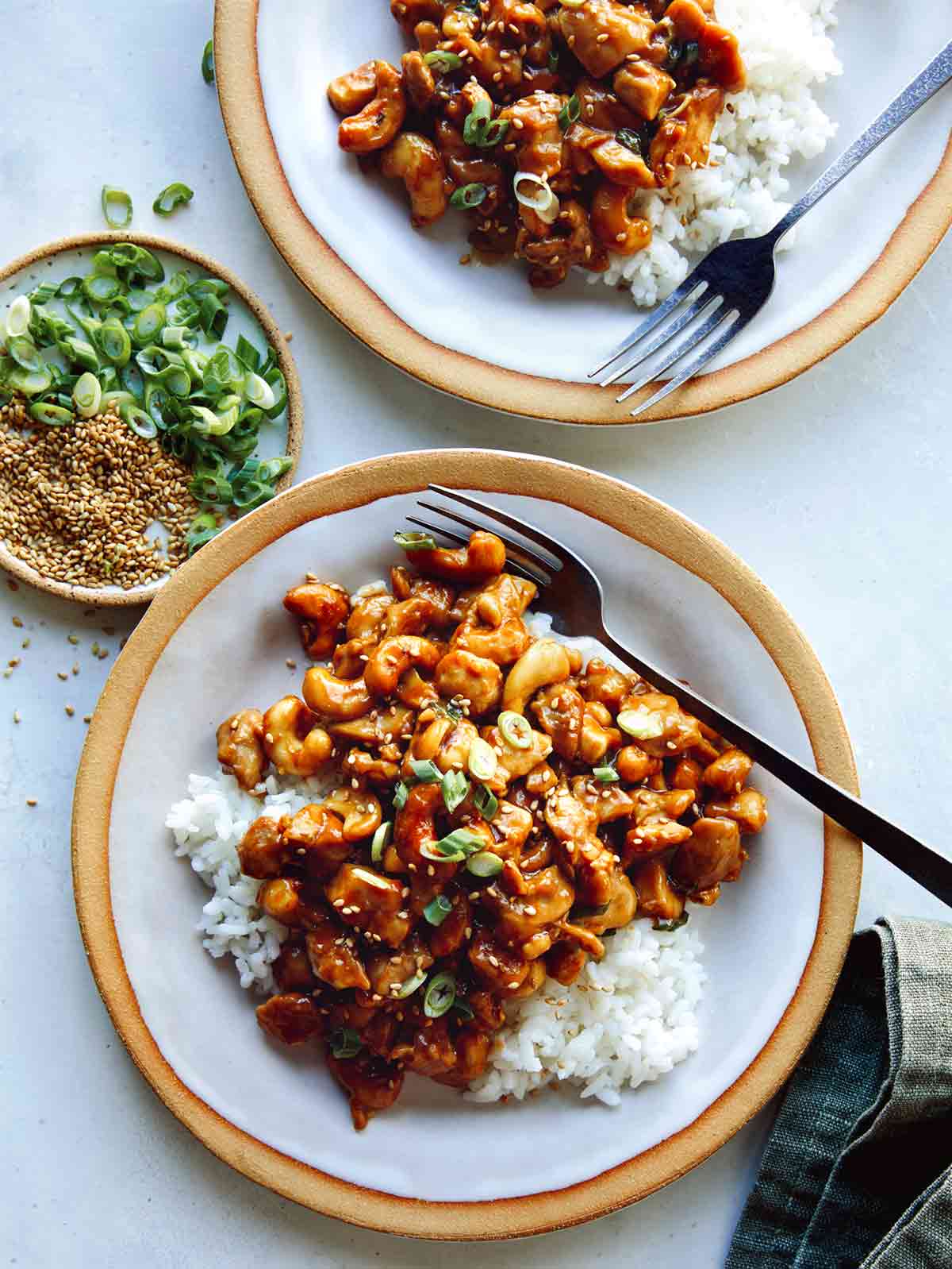 Cashew chicken with on two plates with forks and rice. 