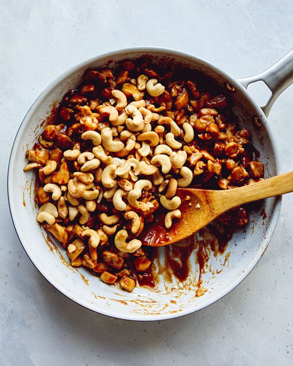Cashews added to chicken and sauce to make cashew chicken.