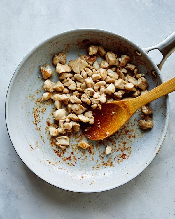 Chicken cooking in a skillet for cashew chicken.