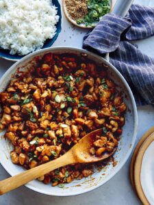 Cashew chicken recipe in a skillet with rice on the side.