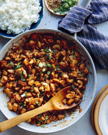 Cashew chicken recipe in a skillet with rice on the side.