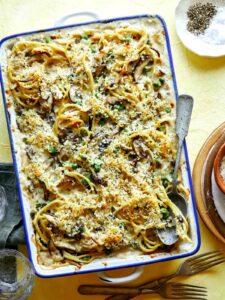 Chicken tetrazzini in a baking dish with a spoon in it ready to sever.