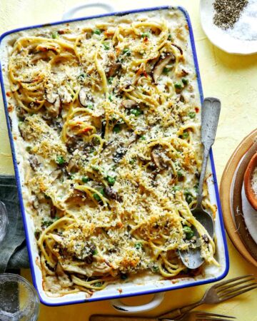 Chicken tetrazzini in a baking dish with a spoon in it ready to sever.