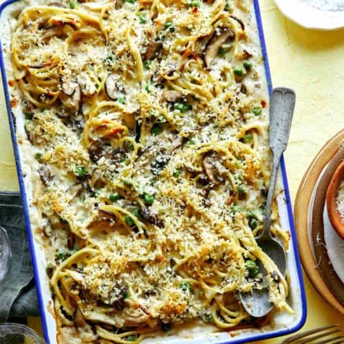 Chicken tetrazzini in a baking dish with a spoon in it ready to sever.