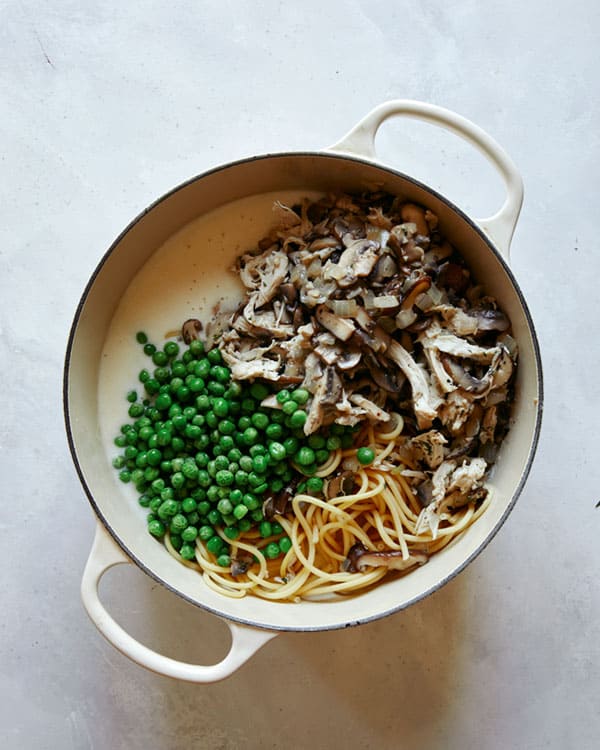 Chicken tetrazzini ingredients being added into the sauce in a stock pot.