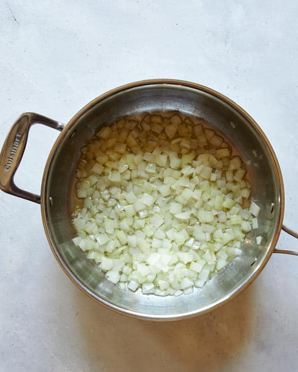 Onions cooking in a skillet with butter.