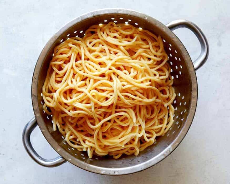 Cooked Chinese style egg noodles sitting in a colander.
