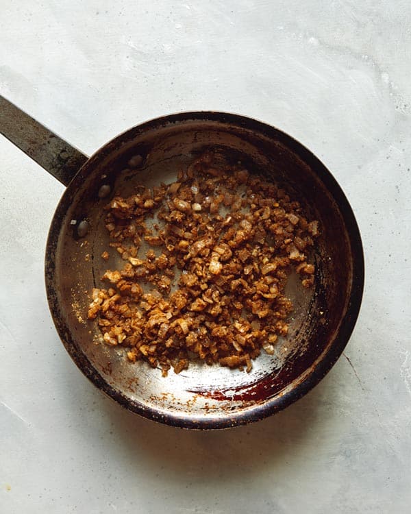 Spices mixed with shallots and garlic in a skillet.