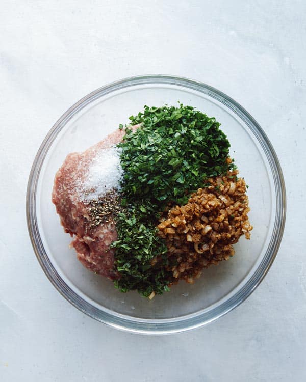 Ground lamb with seasoning in a glass bowl.