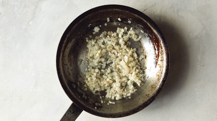 Shallots and garlic cooking in a skillet to make Lamb Kofta.