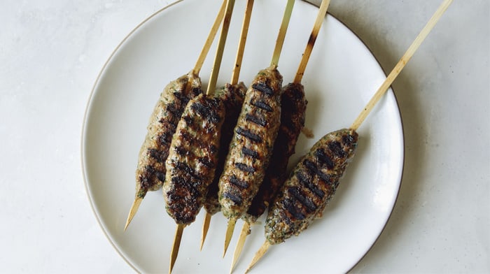 Freshly grilled lamb kofta skewers on a plate.