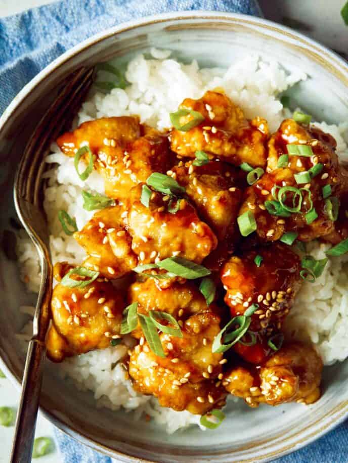 Sesame chicken in a bowl over rice.